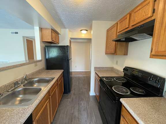 A kitchen with black appliances and wooden cabinets.