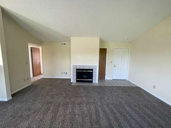 A living room with a fireplace and carpeted floor.