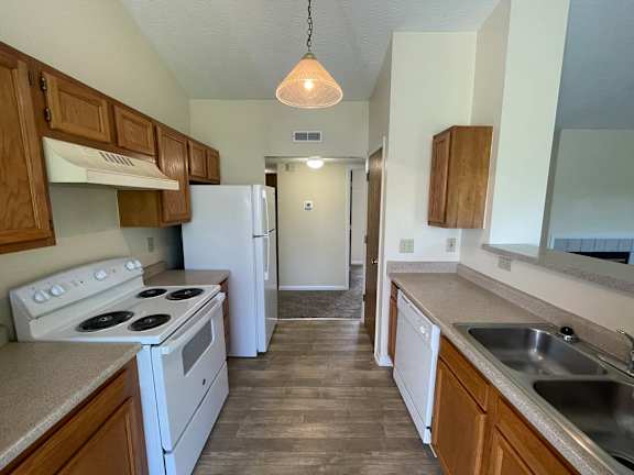 A kitchen with white appliances and wooden cabinets.