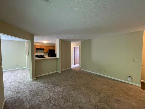 A spacious room with a carpeted floor and a ceiling fan.