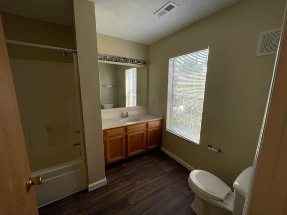 A bathroom with a toilet, sink, and mirror.