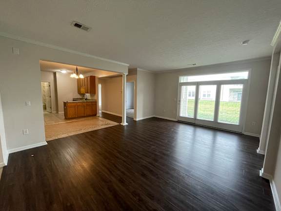 A spacious room with wooden floors and a kitchen area in the background.at Twin Fountains, Mason