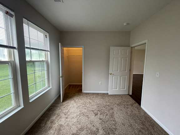 A room with a carpeted floor and a door.at Twin Fountains, Ohio, 45040
