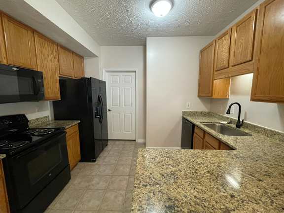 A kitchen with granite countertops and black appliances.at Twin Fountains, Mason, OH