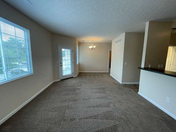 A spacious room with a carpeted floor and a bar area. at The Legends at Steeplechase, Richwood, KY, 41094
