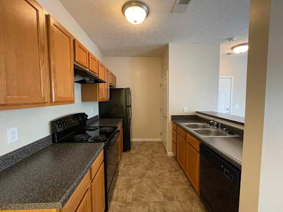 A kitchen with black appliances and wooden cabinets. at The Legends at Steeplechase, Richwood, 41094