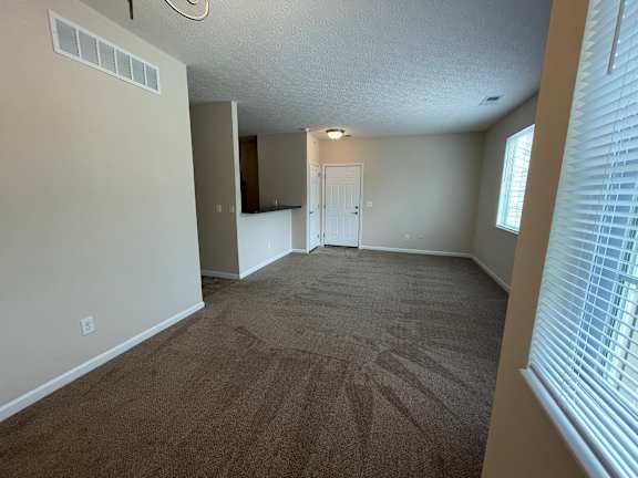 A room with carpeted floor and a door in the background. at The Legends at Steeplechase, Richwood, KY, 41094