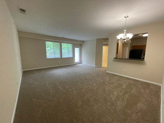 A spacious room with a carpeted floor and a large mirror on the wall. at The Legends at Steeplechase, Richwood, KY