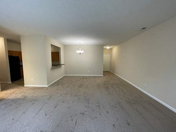 A spacious room with a carpeted floor and a chandelier hanging from the ceiling. at The Legends at Steeplechase, Richwood, 41094