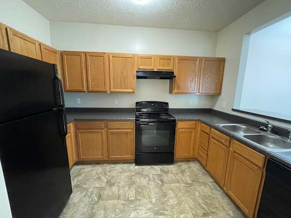 A kitchen with black appliances and wooden cabinets. at The Legends at Steeplechase, Richwood, KY, 41094