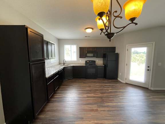 A kitchen with black appliances and wooden floors.