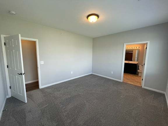 A room with a carpeted floor and two open doors.