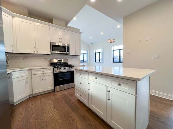A kitchen with white cabinets and a wooden floor.