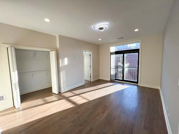 A large empty room with wooden floors and white walls.