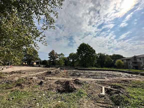 A construction site with a large open area and a few trees in the background.