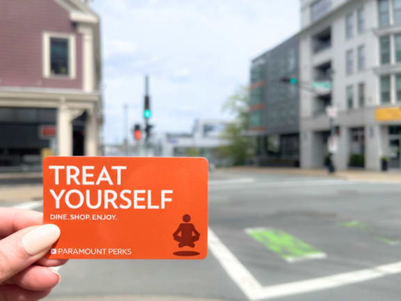 A hand holding a Treat Yourself card from Paramount Perks.