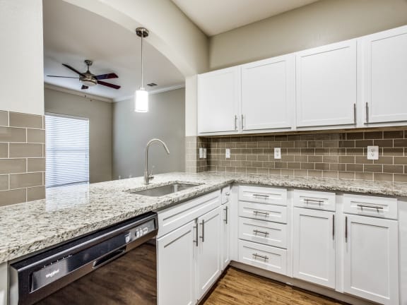 a kitchen with white cabinets and granite countertops at The Canyons Apartments, Fort Worth, TX
