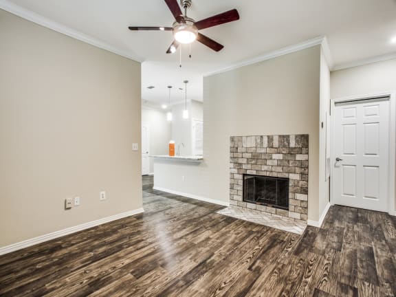 a living room with a fireplace and a ceiling fan at The Canyons Apartments, Fort Worth, TX