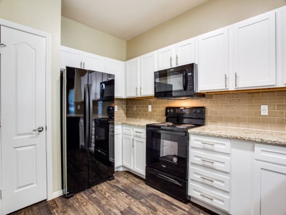 a kitchen with white cabinets and black appliances at The Canyons Apartments, Texas, 76116