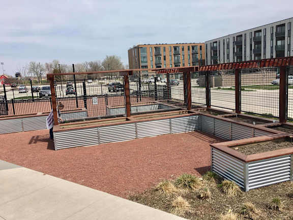 A garden with a pergola and raised beds in front of a building.