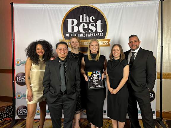 A group of people posing for a photo in front of a banner that says "The Best of Northwest Arkansas."