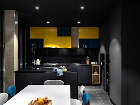 a black kitchen with yellow cabinets and a white table and chairs