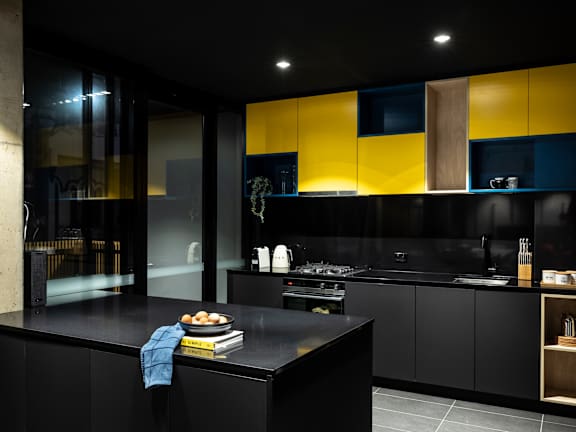 a black and yellow kitchen with yellow cabinets and black countertops