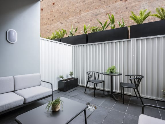 a patio with a table and chairs and a white fence