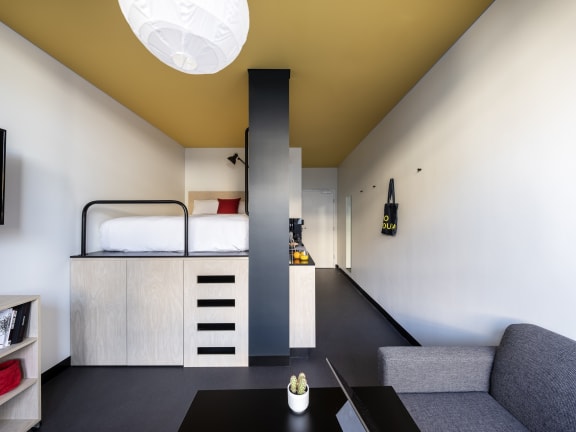 a bedroom with a bunk bed and a desk in a room with a yellow ceiling