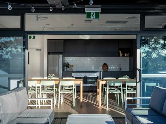 a living room with tables and chairs and a kitchen