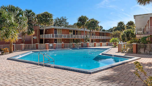 a swimming pool in front of a hotel with palm trees
