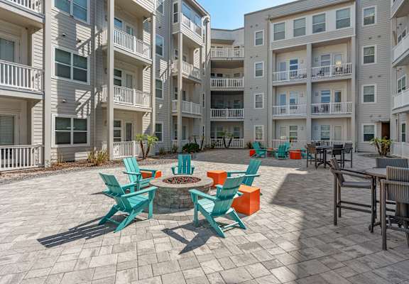 A sunny day at a courtyard with blue chairs and orange cushions at Lake Lofts at Deerwood, Jacksonville, FL, 32216