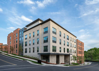 A modern multi-story building with a parking lot in front.
