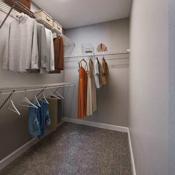 A walk in closet with clothes hanging on shelves.