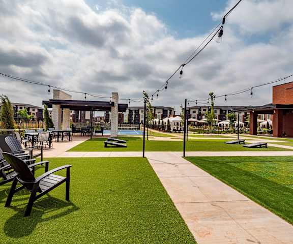 The courtyard at 35 Degrees with cornhole sets, chairs, and a sports court in the background. 