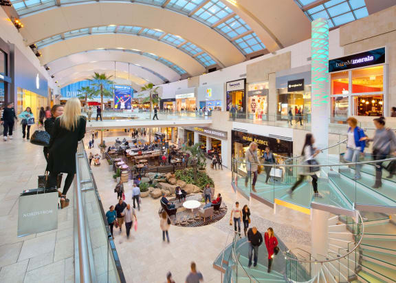 A shopping mall with people walking around and stores on either side. at Lombardi Apartments, Woodland Hills, 91367