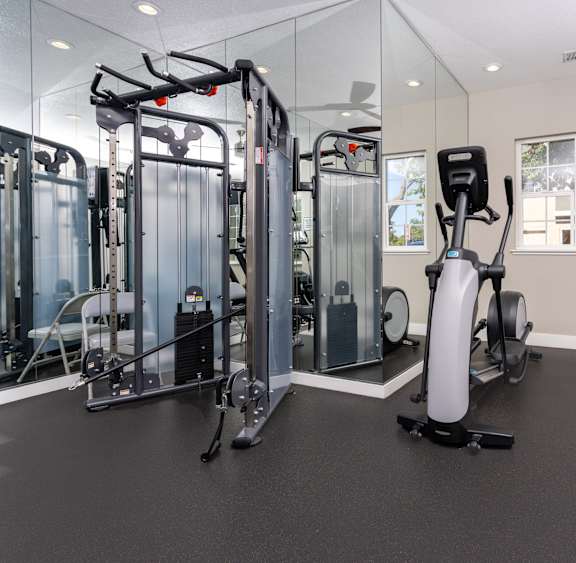 A gym with a variety of equipment including treadmills, stationary bikes, and elliptical machines.