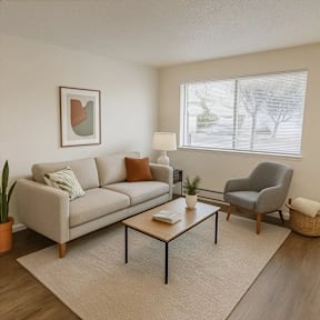 A living room with a grey sofa, a grey armchair, a wooden coffee table, and a framed artwork on the wall.
