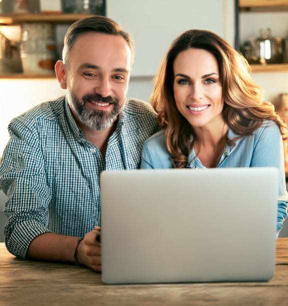 a man and woman sitting at a table with a laptop