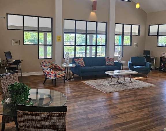 a living room with couches chairs and tables and windows
