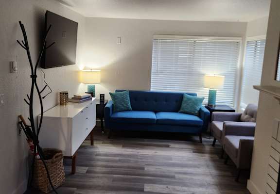 A living room with a blue couch and a wooden floor.