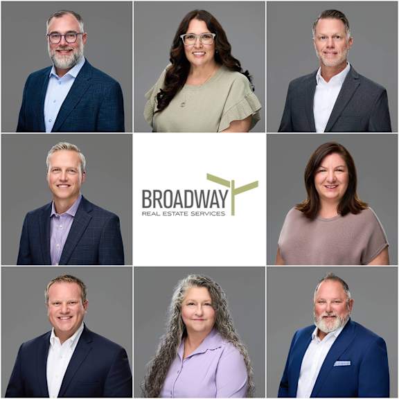 A group of people are posing for a professional photo with the logo of Kim Carpenter Poster and Broadway Real Estate Services.
