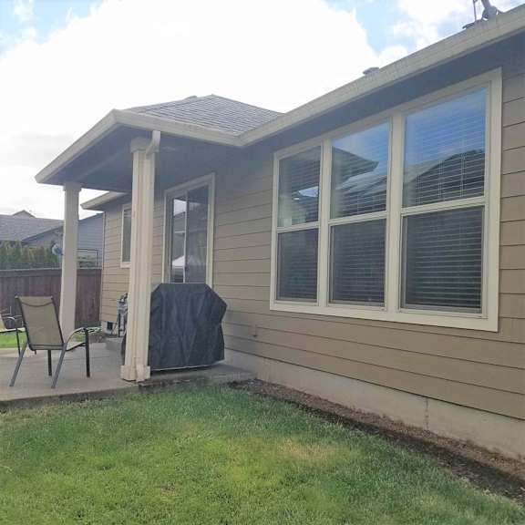 a patio with a chair and a table in front of a house
