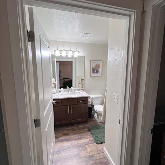 A bathroom with a toilet, sink, and mirror.