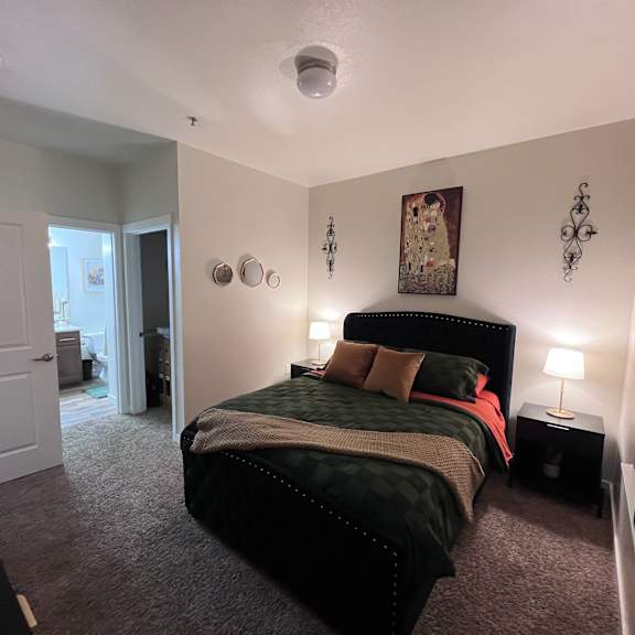 A bedroom with a bed, nightstand, and lamp.