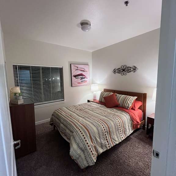 A bedroom with a bed, nightstand, and a picture on the wall.