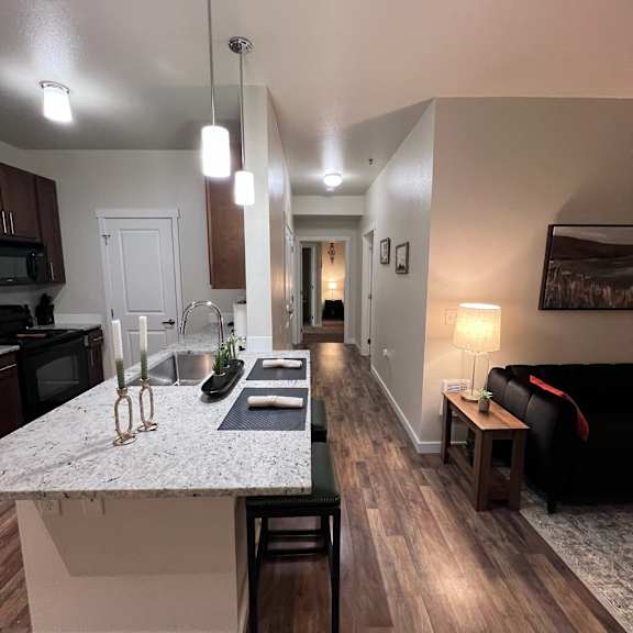 A kitchen with a marble countertop and wooden floors.