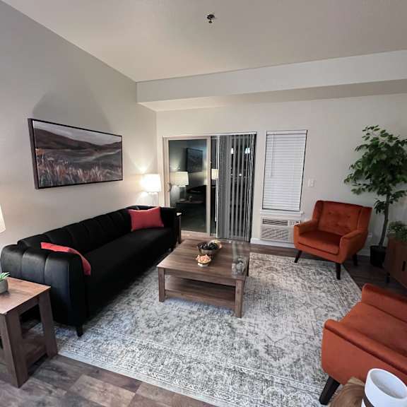 A living room with a black couch, a coffee table, and a red chair.