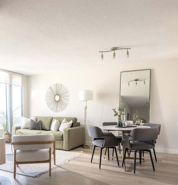 a living room with a table with chairs and a couch and a mirror