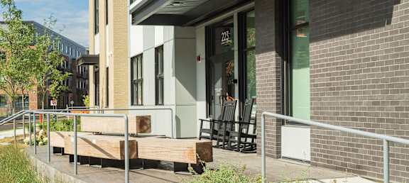 A building with a balcony and a flower bed in front.